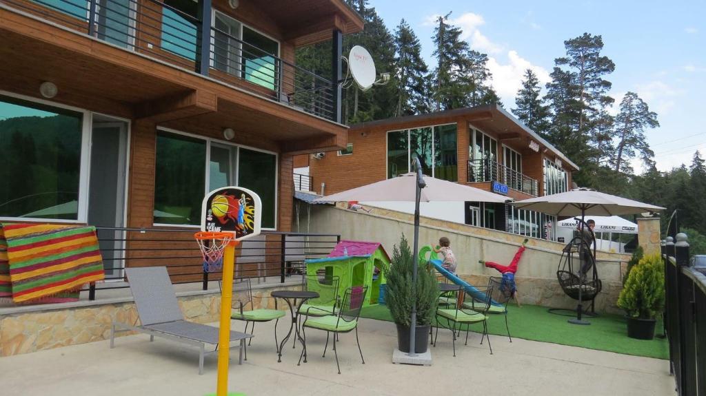 a house with a patio with chairs and tables at Chalet Kokhta in Bakuriani