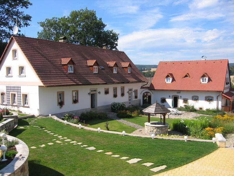 a white house with a red roof and a yard at Čapkův statek in Hořičky
