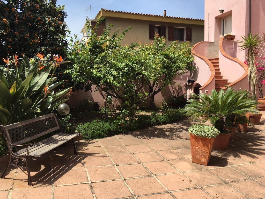 un banco en un jardín con plantas y una casa en Affittacamere Ciro's House, en Olbia