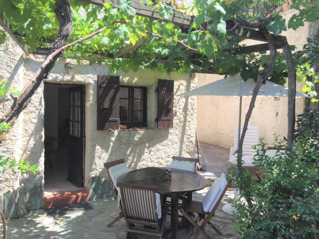 een patio met een tafel en stoelen en een parasol bij Les Hameaux de Propriano in Propriano