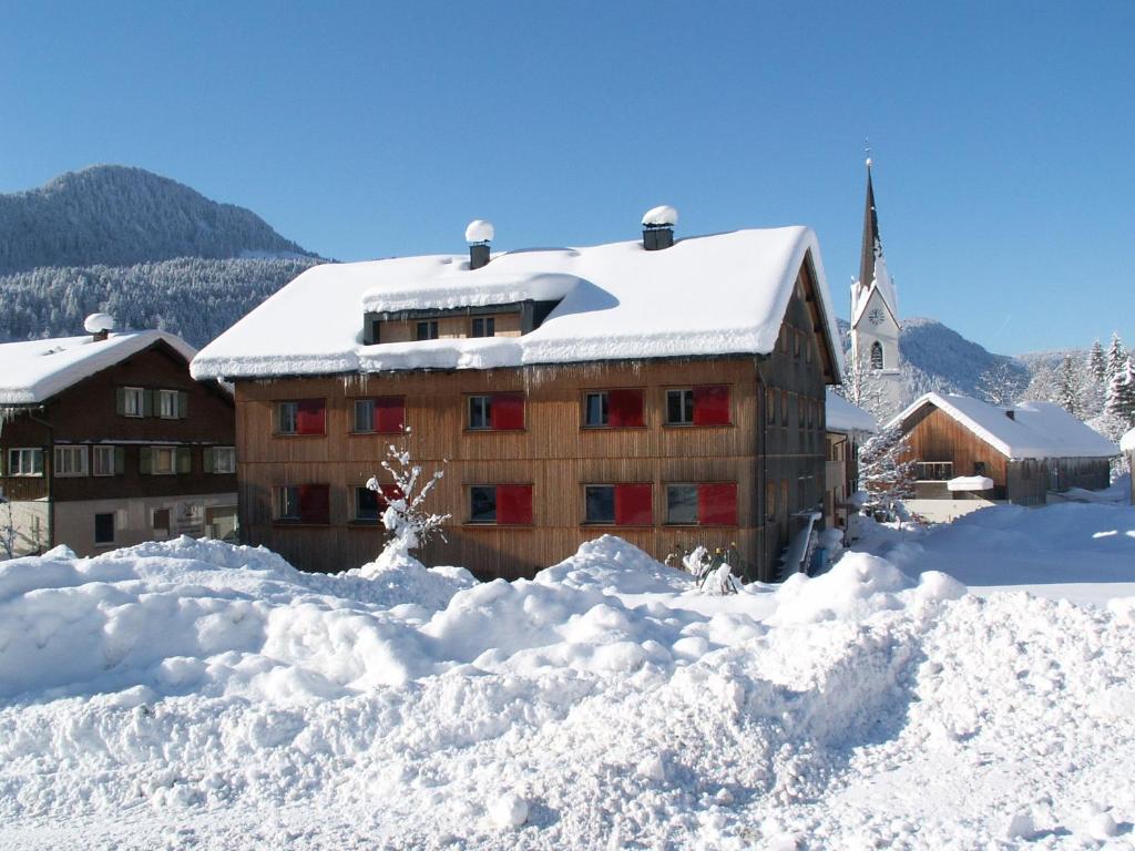 een gebouw bedekt met sneeuw naast een berg sneeuw bij Gasthof Taube in Bizau