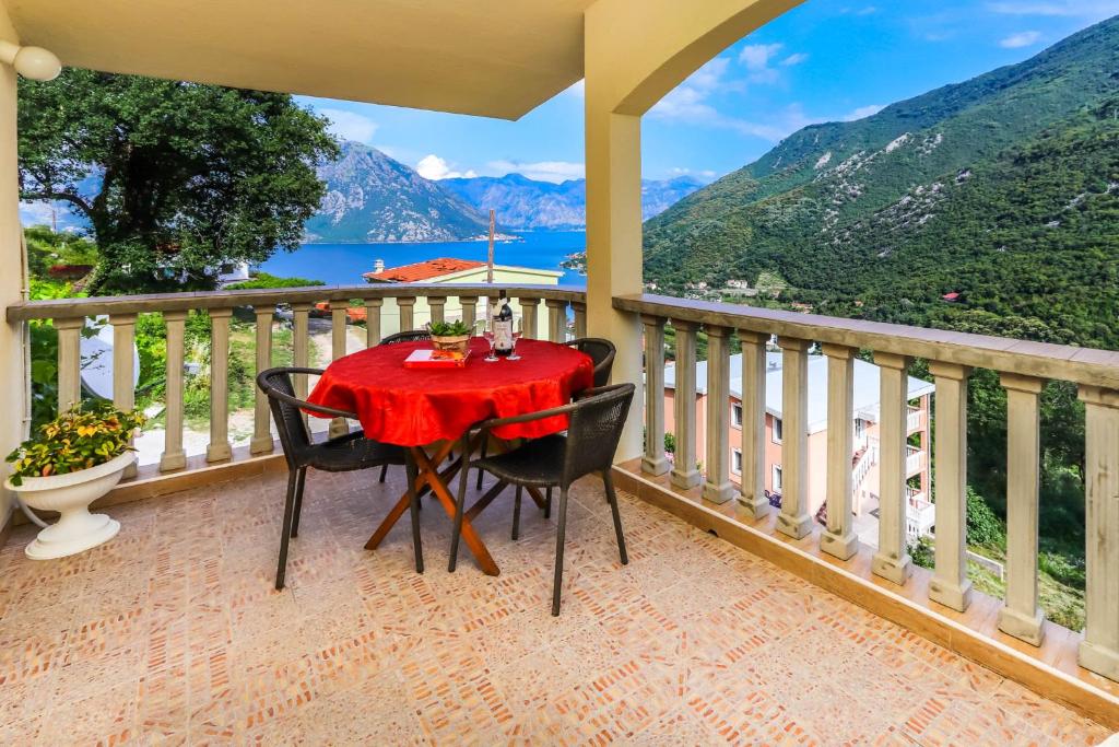 a table on a balcony with a view of the mountains at Apartments Zeko in Donji Morinj