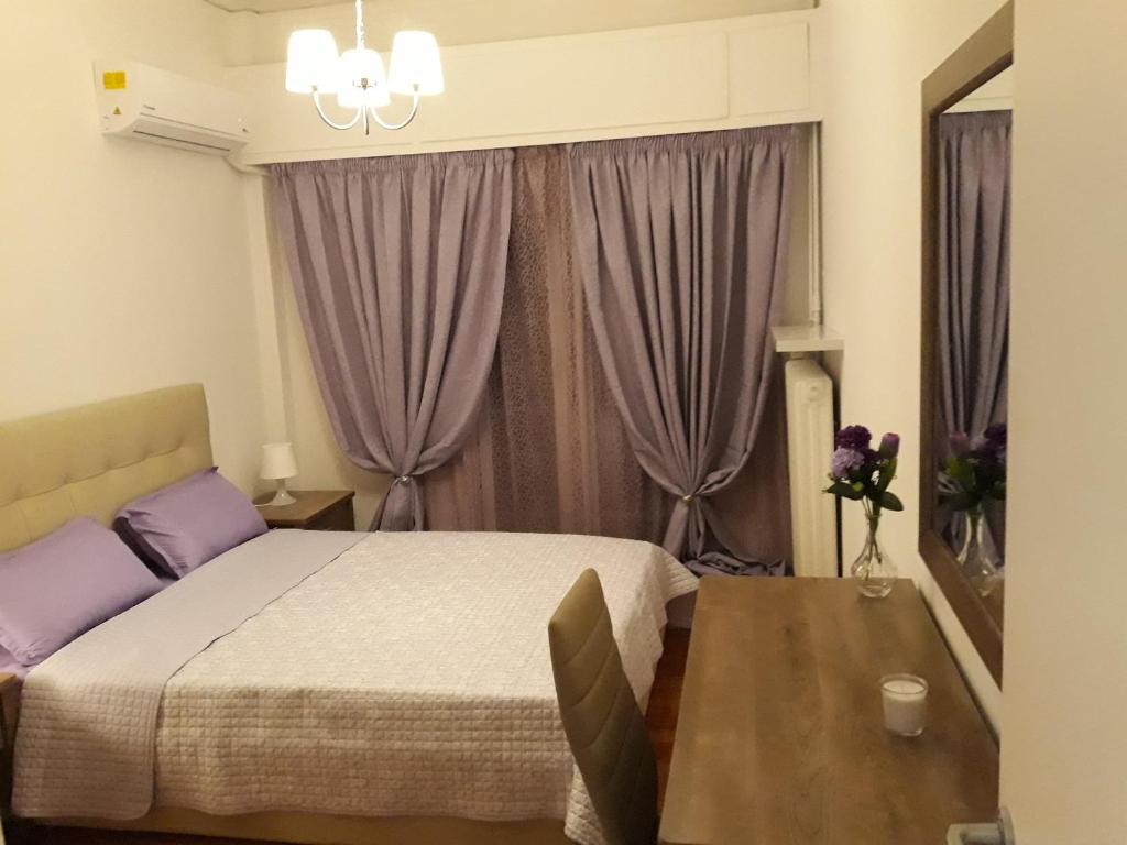 プレベザにあるMarilias Apartment Prevezaのベッドルーム1室(ベッド1台、テーブル、紫色のカーテン付)