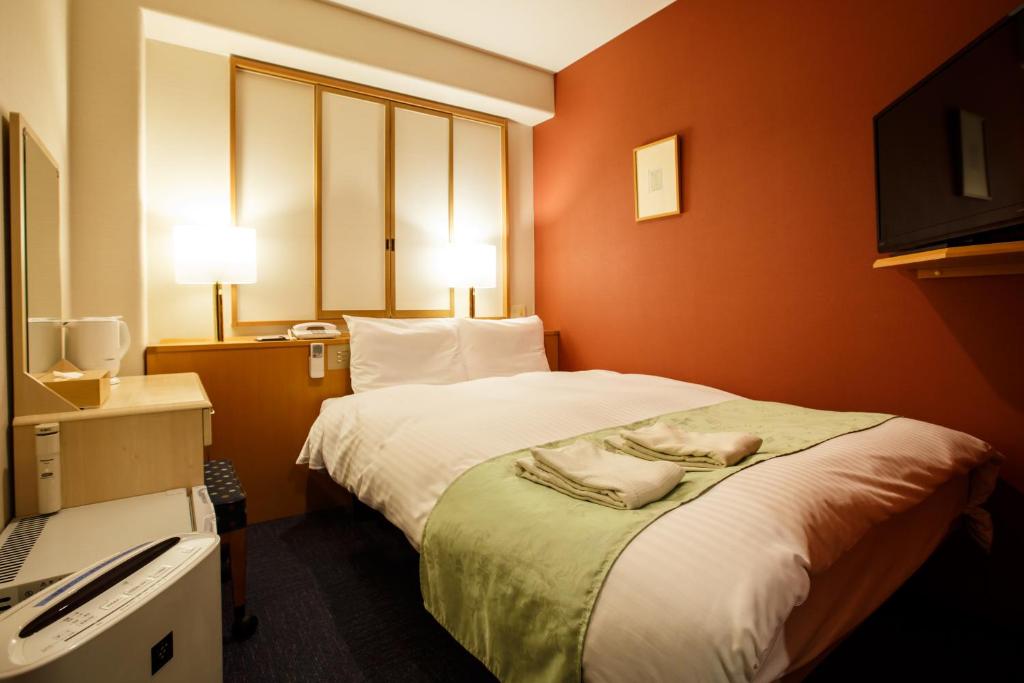 une chambre d'hôtel avec un lit et une télévision dans l'établissement Fukuoka Floral Inn Nishinakasu, à Fukuoka