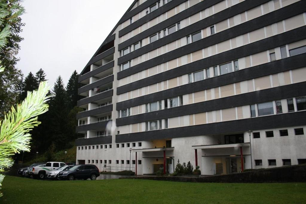 a large building with cars parked in front of it at Apartmenthaus Gauenpark - CharmingStay in Flumserberg