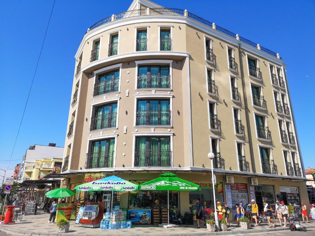a tall building with green umbrellas in front of it at Empera H-l in Sunny Beach