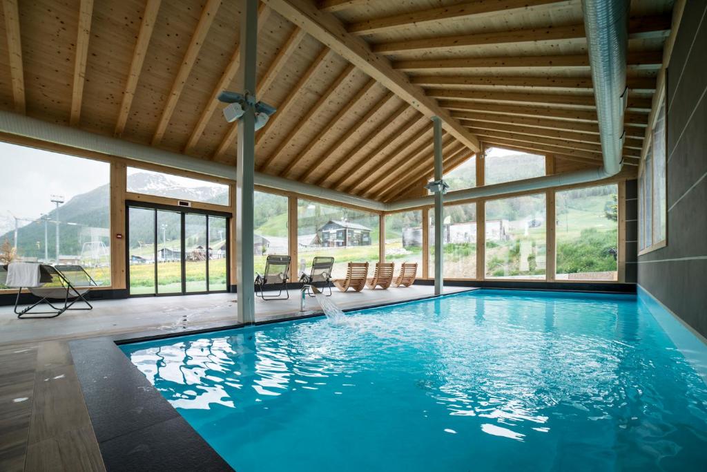 a swimming pool in a house with a wooden ceiling at Hotel Alba in Livigno