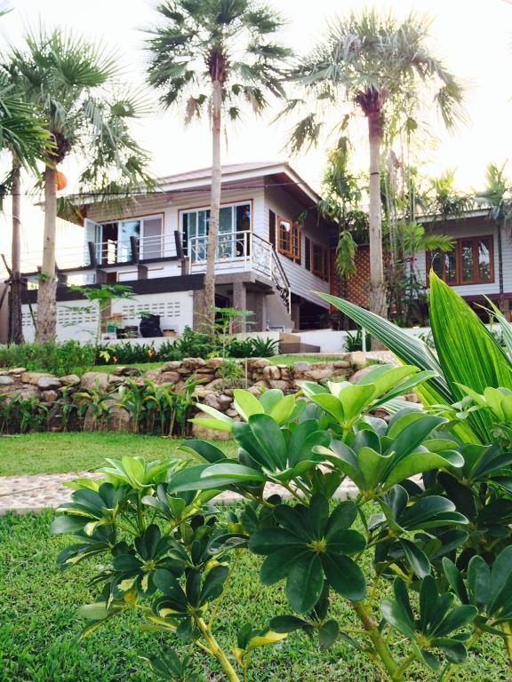 a house with palm trees in front of it at Magmai Riverside in Tak