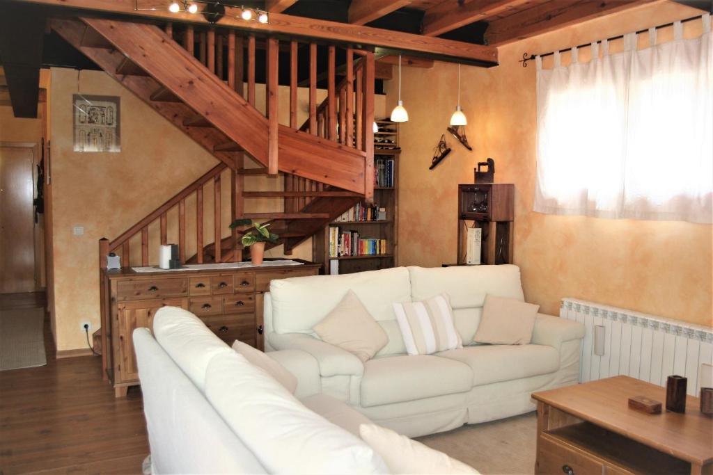 a living room with a white couch and a staircase at Apartamento Mirador De Masella in Puigcerdà