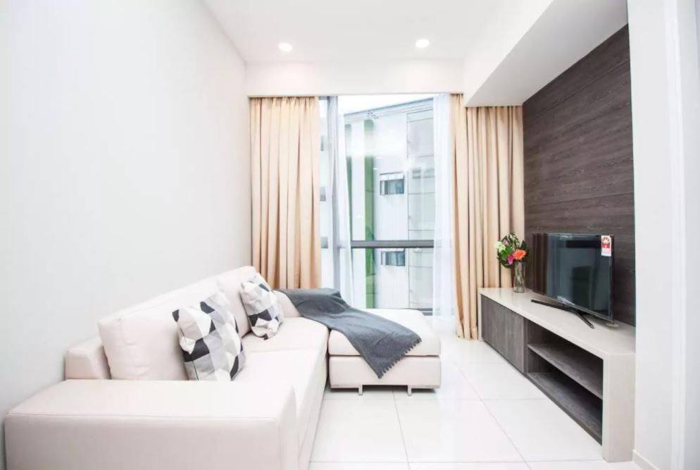 a white living room with a white couch and a tv at The Robertson KL in Kuala Lumpur