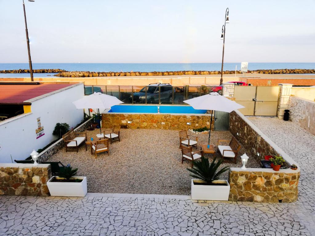 a patio with chairs and umbrellas and a pool at Albachiara Guest House in Fiumicino