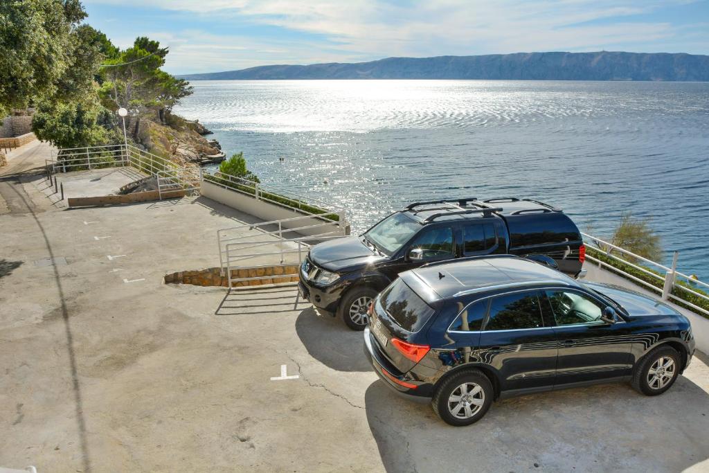 two cars parked next to a body of water at Apartments Miki in Donja Klada