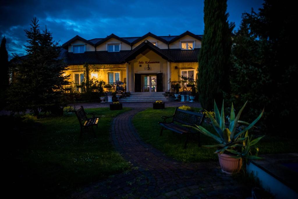 a large house at night with a pathway in front at Lodownia in Szydłowiec