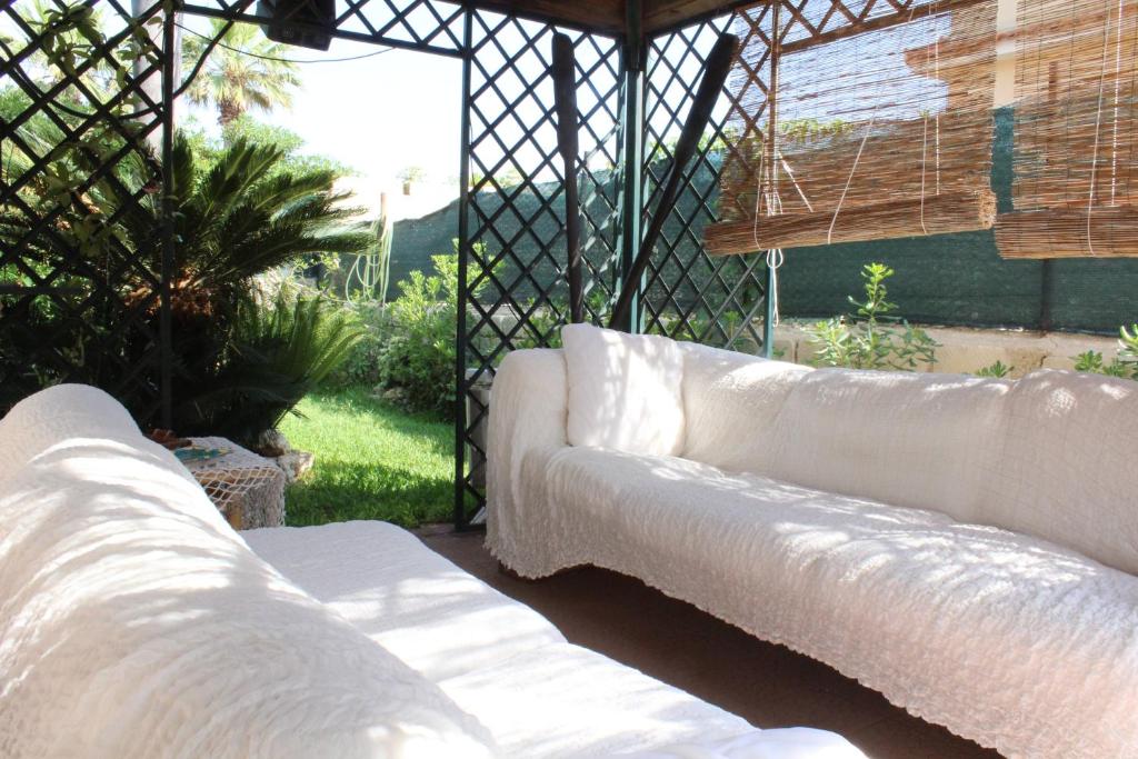 a living room with white couches in a garden at Villa Aurora in Ognina