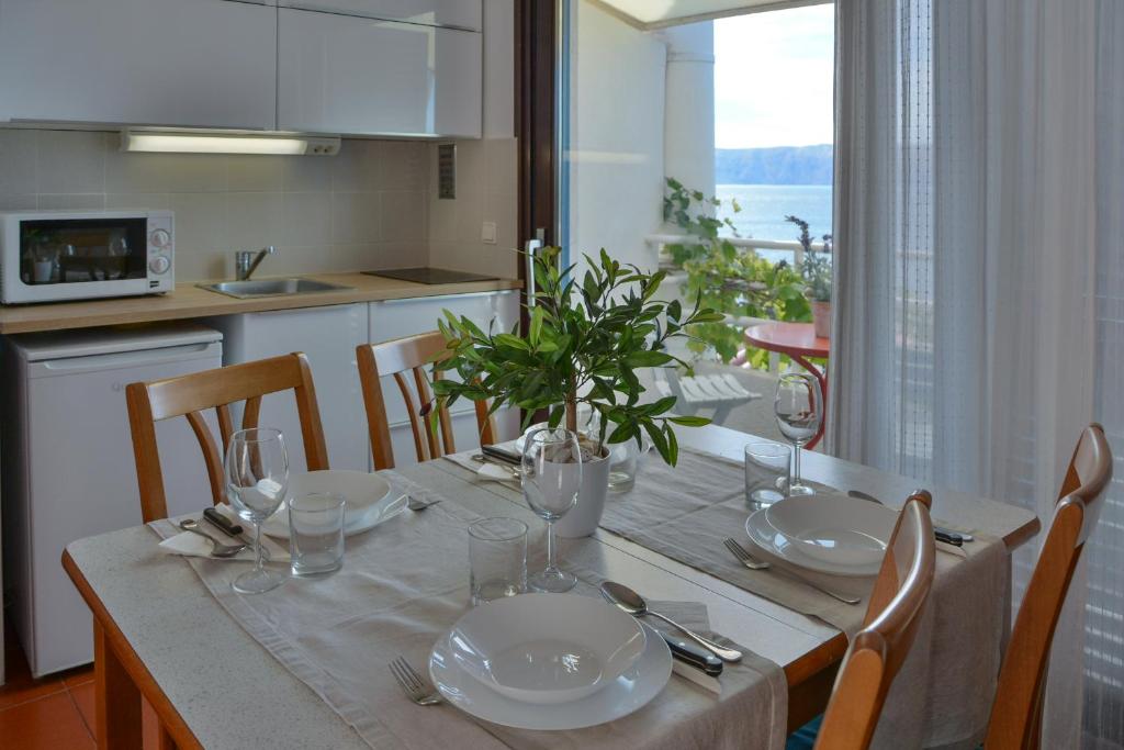 a dining table with plates and glasses and a plant on it at Apartments Miki in Donja Klada