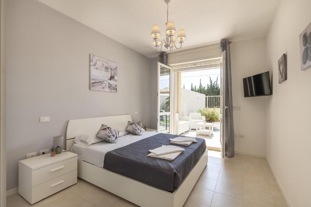 - une chambre blanche avec un lit et un balcon dans l'établissement Le Domus lovely apartment, à Quartu SantʼElena