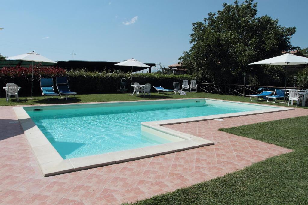 a swimming pool with chairs and umbrellas in a yard at Agriturismo Le Stringaie in Montepulciano Stazione