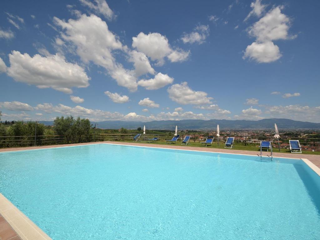 una gran piscina con sillas y un cielo en Belvilla by OYO La Casa dei Cinque Olivi en Quarrata