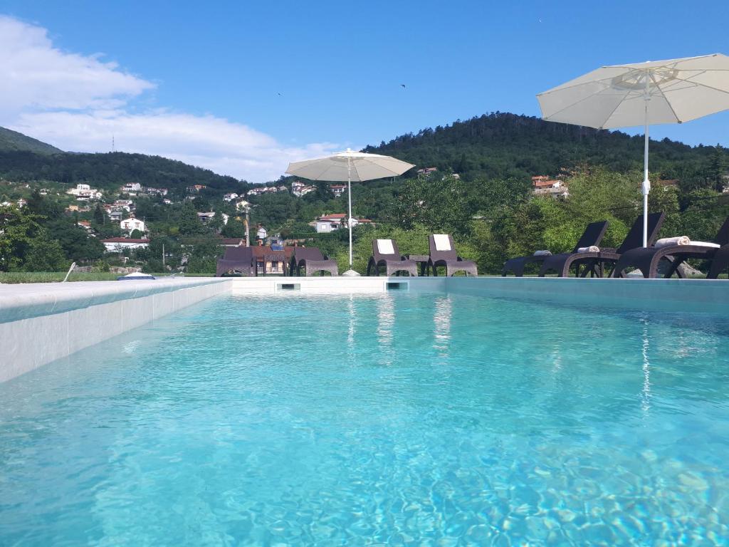a swimming pool with blue water and an umbrella at Guest House Stancija Kovacici in Opatija