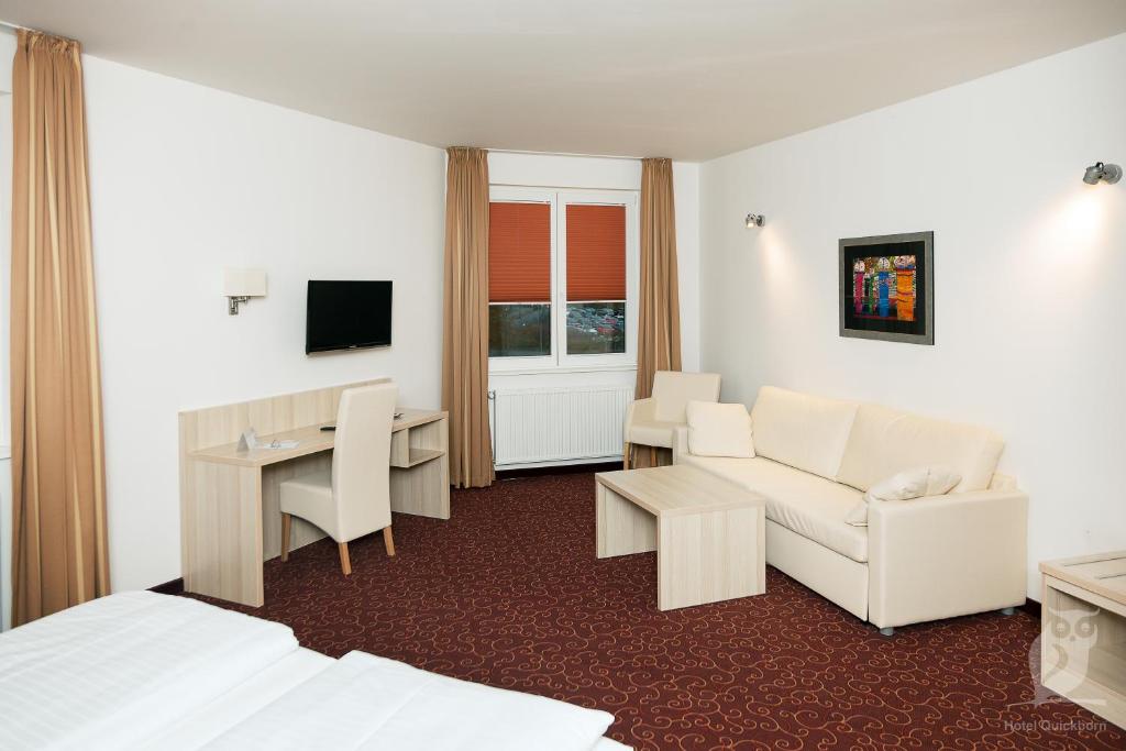 クイックボルンにあるホテル クイックボルン ＆ ガステハウス ヘッセンのベッド、ソファ、デスクが備わるホテルルームです。