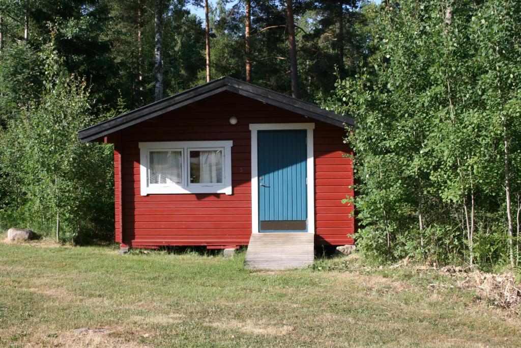 Cabaña roja con puerta azul y ventana en Borggården stugor, en Hultsfred