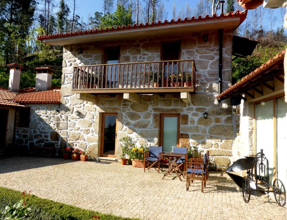una casa in pietra con balcone, tavolo e sedie di Casa da Eira Velha a Vale de Cambra