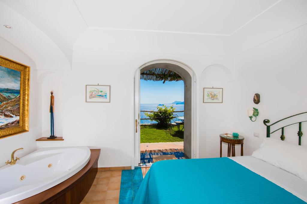 Schlafzimmer mit Badewanne, Bett und Fenster in der Unterkunft Calante Luna in Praiano