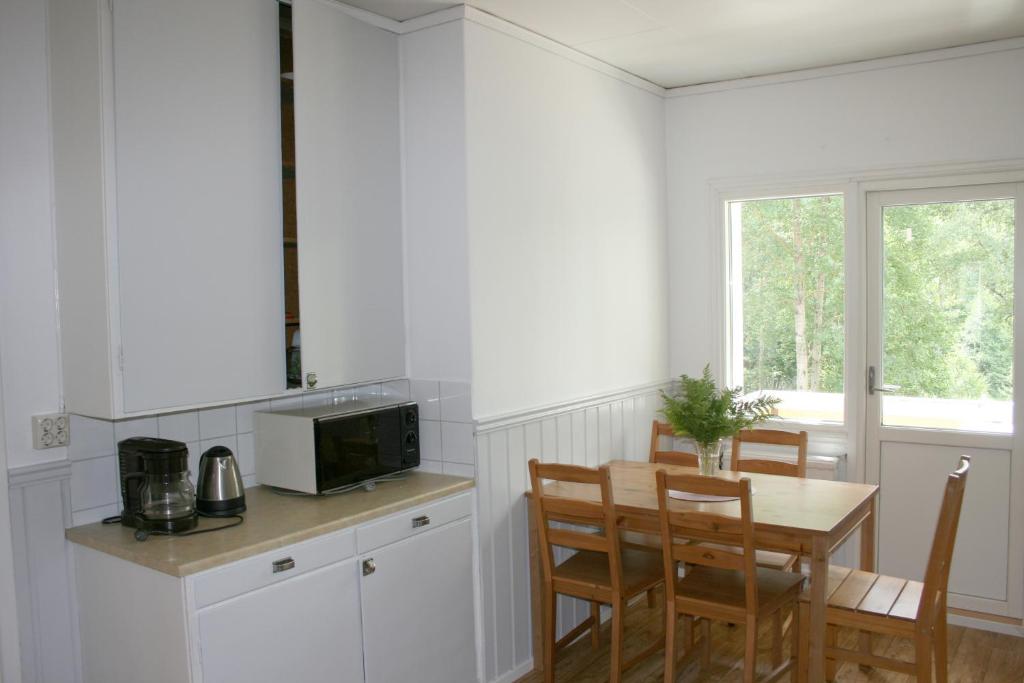 uma cozinha com uma mesa e cadeiras e um micro-ondas em Borggården Apartment em Hultsfred