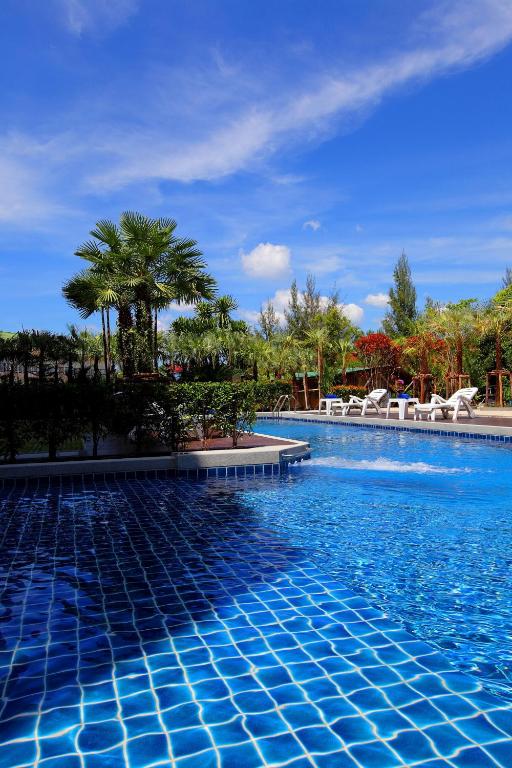 a blue swimming pool with chairs and palm trees at Sungthong Kamala Beach Resort in Kamala Beach