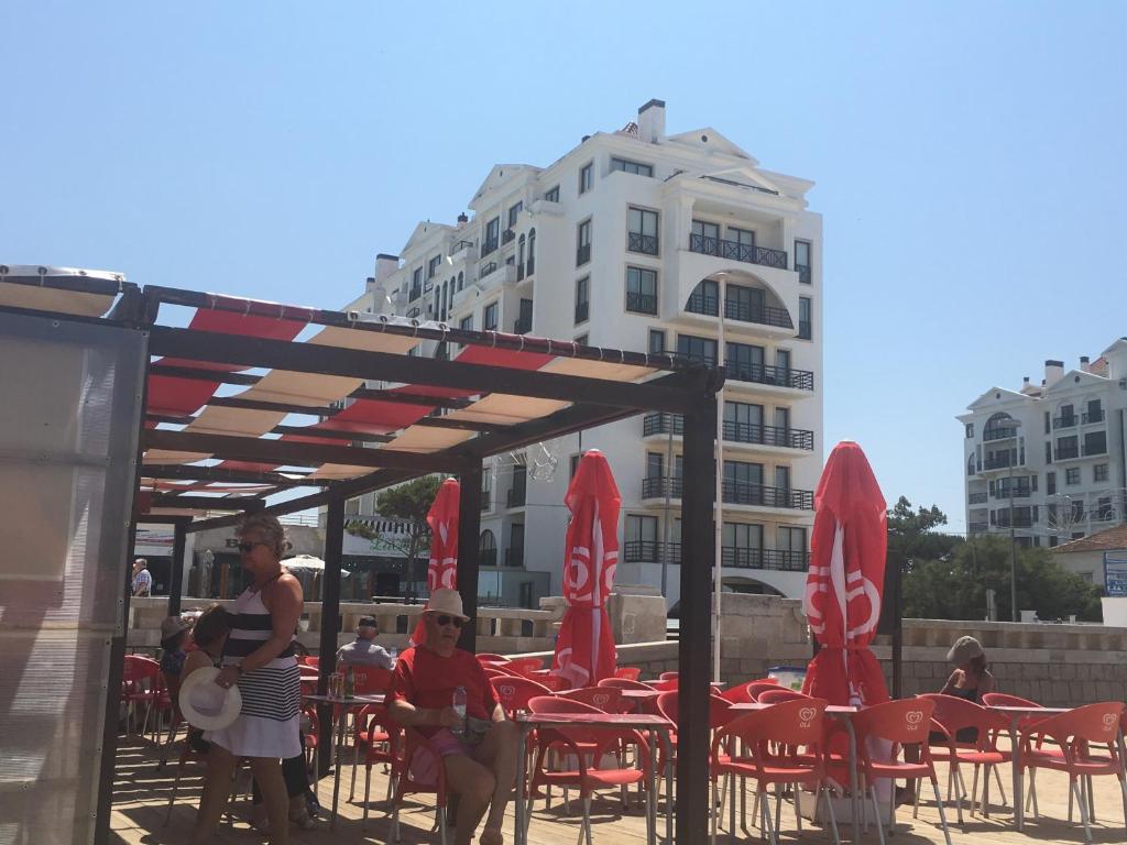 un grupo de personas sentadas en una mesa con sillas y sombrillas en Beachfront 3bdr apt on Marginal Boulevard, en São Martinho do Porto