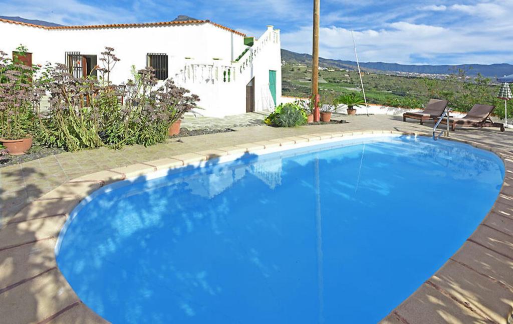 a blue swimming pool in front of a house at Casa Amagar in Tijarafe