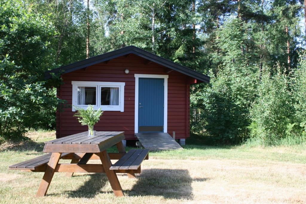 un pequeño cobertizo con una mesa de picnic y un banco de picnic delante de él en Modal Stugor, en Hultsfred