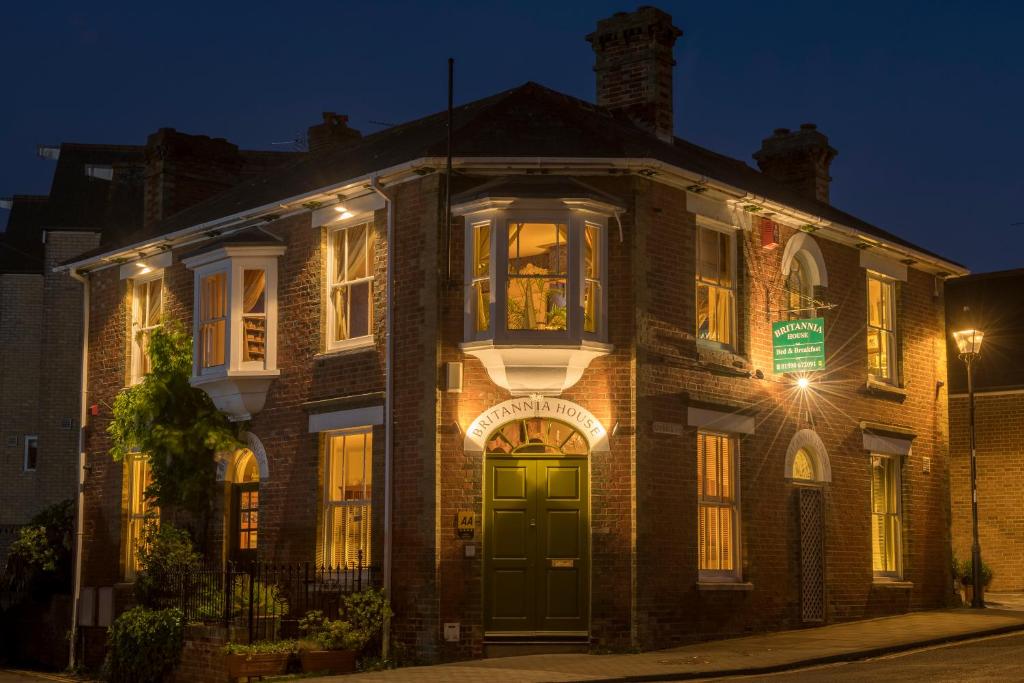 uma velha casa de tijolos com uma porta verde à noite em Britannia House em Lymington