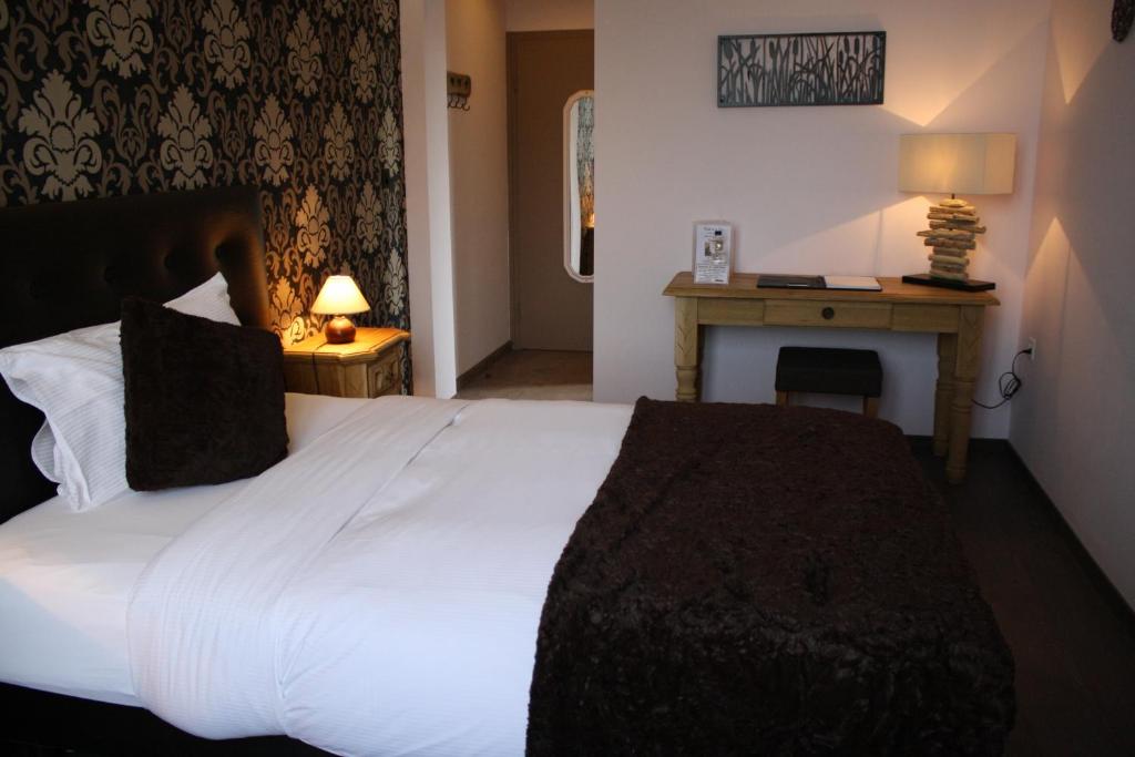 a bedroom with a large white bed and a desk at Hotel de la Gare in Monthey