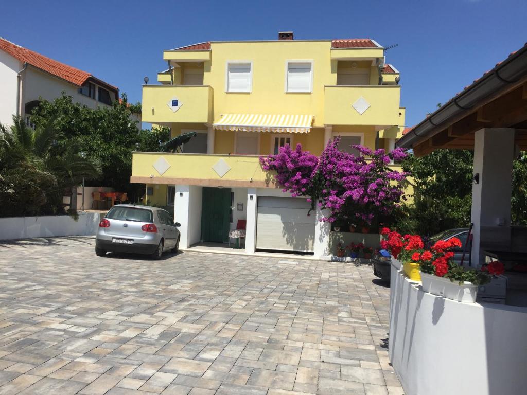 a car parked in front of a yellow building at Apartmani Saric A&K in Vir