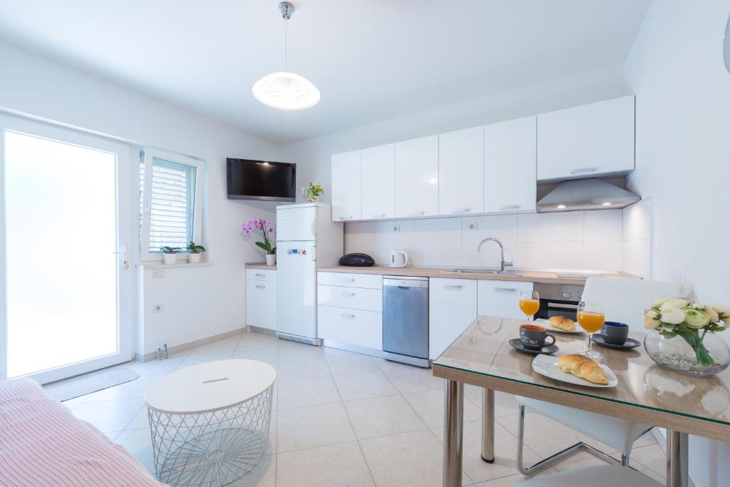 a kitchen with white cabinets and a table with food on it at Apartman Lu in Mokošica