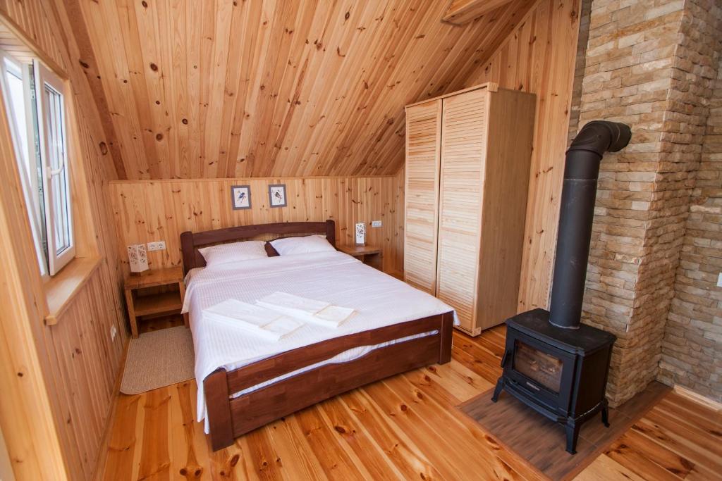 1 dormitorio con 1 cama y estufa de leña en Ostrivky, en Svityazʼ