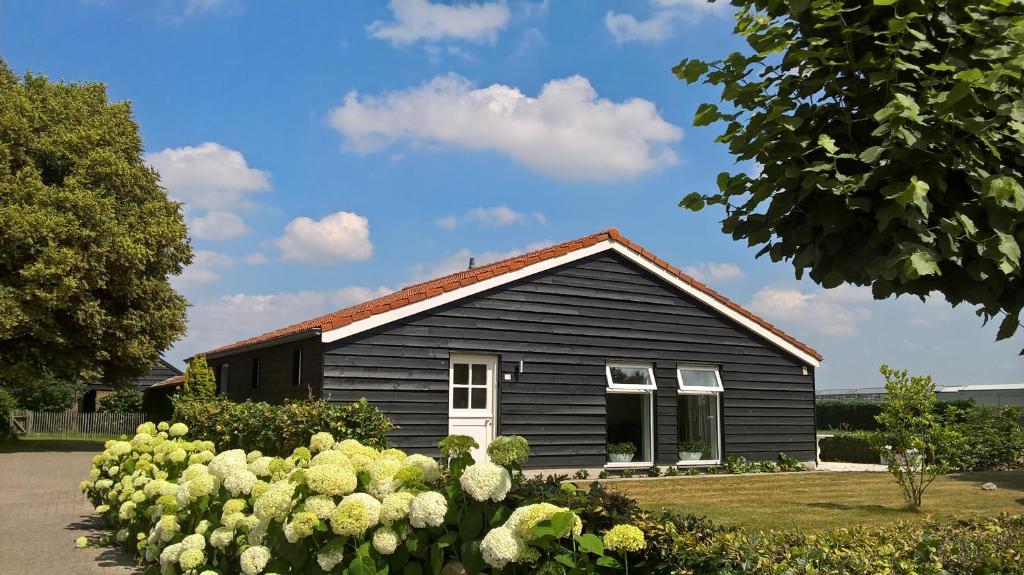 ein schwarzes Haus mit Garten davor in der Unterkunft Boeren Burgers Buitenlui in Molenschot