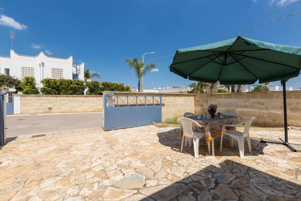 een patio met een tafel en een groene parasol bij Villino Gemma Celeste by BarbarHouse in Torre Lapillo