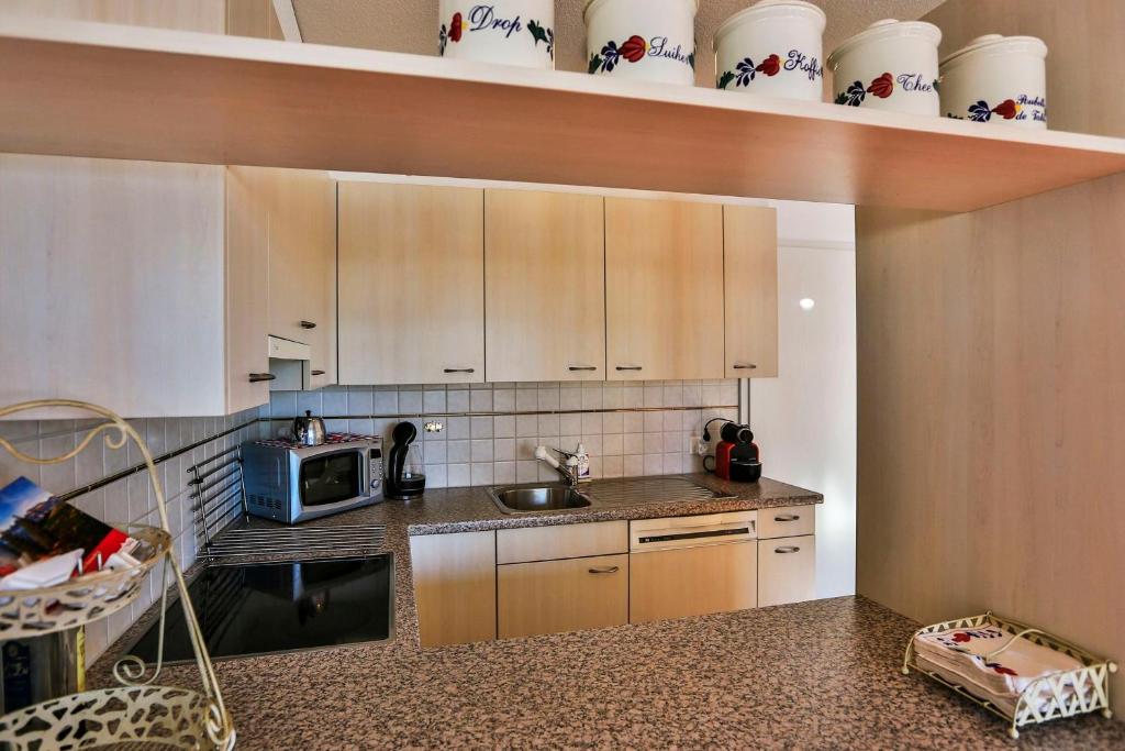 eine Küche mit einer Spüle und einer Mikrowelle in der Unterkunft Haus Flumser-Hockli - CharmingStay in Flumserberg