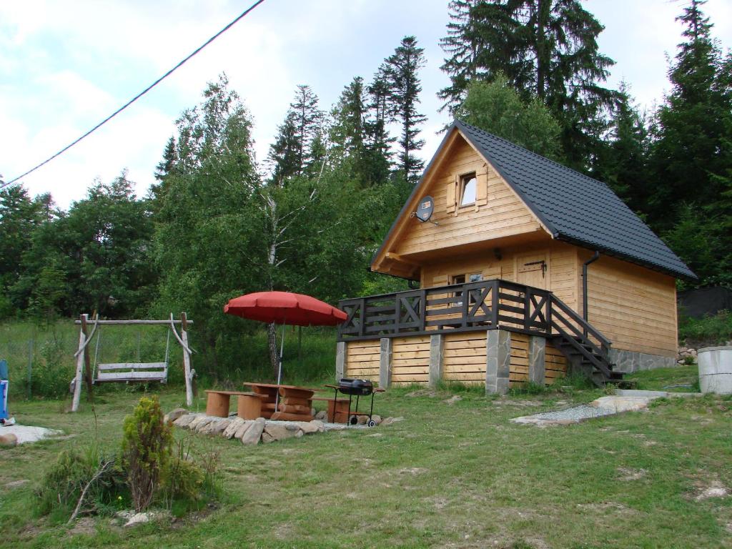 a log cabin with a red umbrella and a table at Villa Róża in Kamesznica