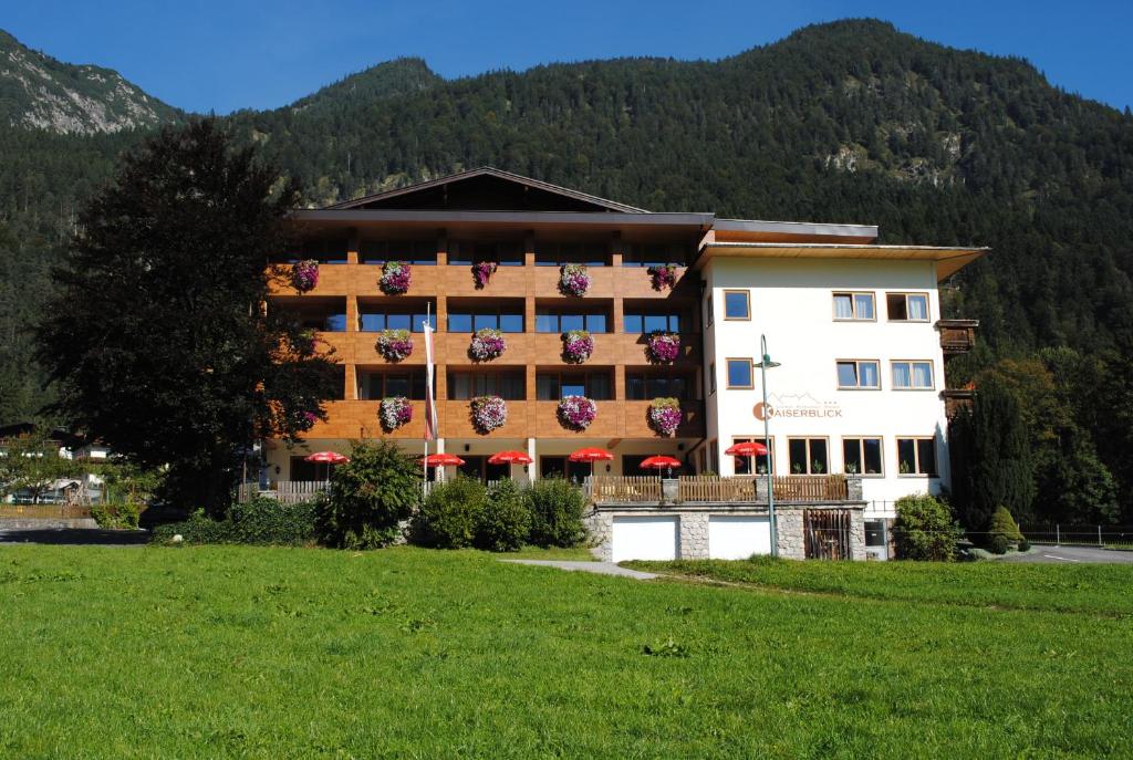 a hotel in the mountains with a green field at Gasthof Kaiserblick in Breitenbach am Inn