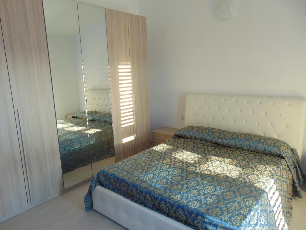 Schlafzimmer mit einem Bett und einem Spiegel in der Unterkunft Villetta La Caletta in Siniscola