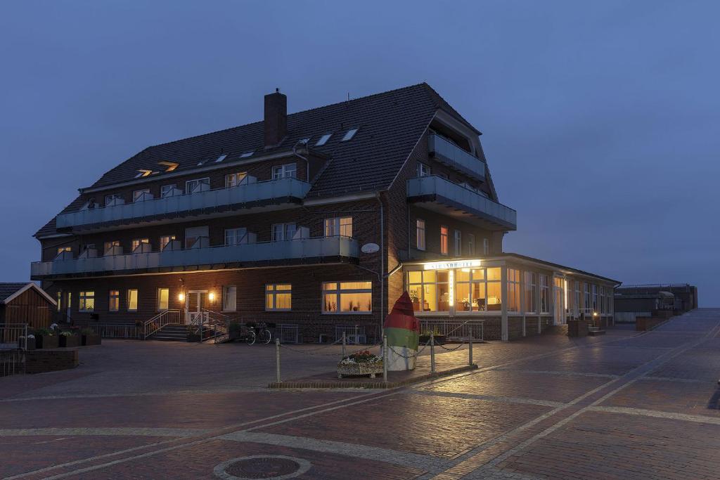 d'un grand bâtiment éclairé dans un parking. dans l'établissement Strandhotel Wietjes, à Baltrum