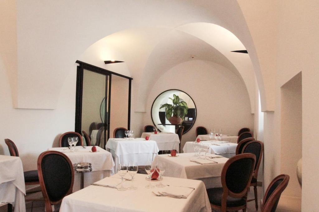 a restaurant with white tables and chairs and a mirror at Grand Hotel Masseria Santa Lucia in Ostuni