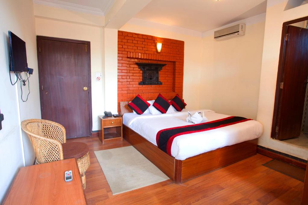 1 dormitorio con 1 cama con pared de ladrillo en Hotel Atlantic, en Katmandú