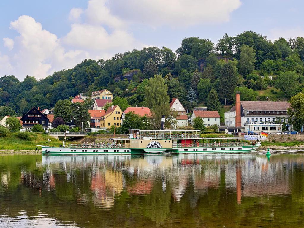 two boats are docked on the water near a town at Hotel Elbparadies in Pirna