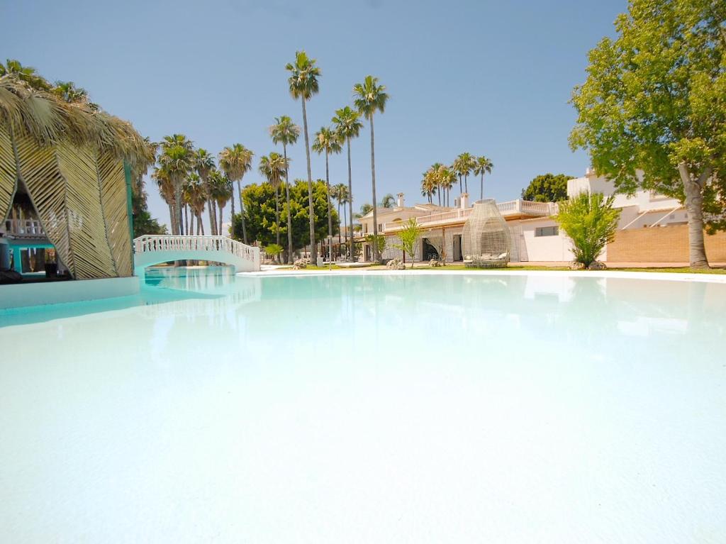 een groot zwembad met palmbomen op de achtergrond bij Tu&Me Resort - Adults Only in Gandía