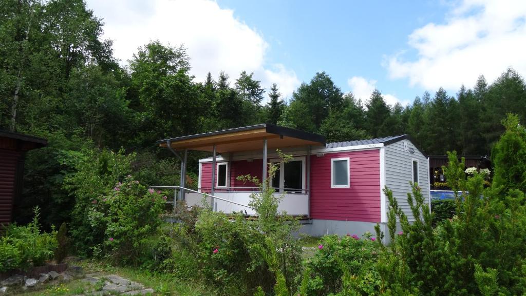 a red and white tiny house in the woods at Camping Harfenmühle - Mobilheim in Mörschied