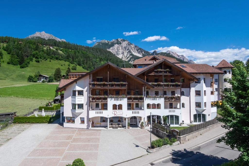 a large white building with mountains in the background at Residence Rautal B&B ***S in San Vigilio Di Marebbe